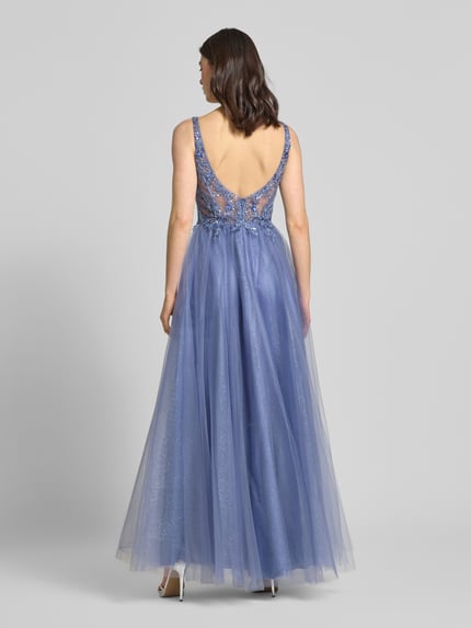 Modelka kobieca nosi 'Abendkleid aus Tüll mit Stitchings und Pailletten' od Unique, fioletowy tiul, zdobienia, krój A-linii, długość midi, szerokość w rozmiarze 36: 33 cm, długość z tyłu w rozmiarze 36: 126 cm, widok całej sylwetki od tyłu.