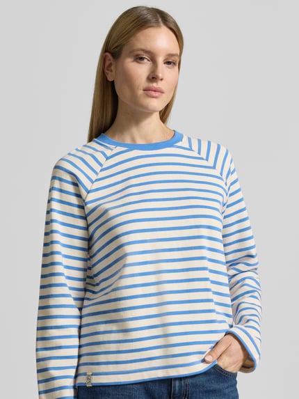 Frauenmodel trägt Sweatshirt mit Raglanärmeln Modell 'Lidy' von MOS MOSH aus Reine Baumwolle, Lockerer-Schnitt, Rundhalsausschnitt, gestreift in Blau und Creme, strukturierte Oberfläche, Ganzkörperansicht von vorne.