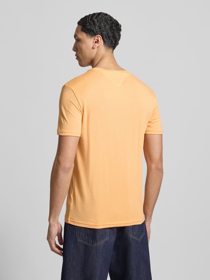 Männermodel trägt Slim Fit T-Shirt aus Baumwoll-Mix Modell 'JASPE HERITAGE' von Tommy Jeans in Melange-Optik, Ganzkörperansicht Rückansicht.