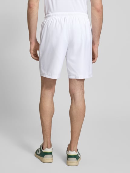 Männermodel trägt Relaxed Fit Sport-Shorts mit Logo-Stitching von Lacoste, Optik: Unifarben, Bundabschluss: elastisch, Ganzkörperansicht Rückansicht.