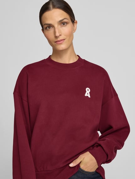Vrouwenmodel draagt bordeauxrood oversized sweatshirt uit pure katoen model 'ALIZAA' van ARMEDANGELS, Dames sweatshirt, Nahaufnahme Oberkörper.