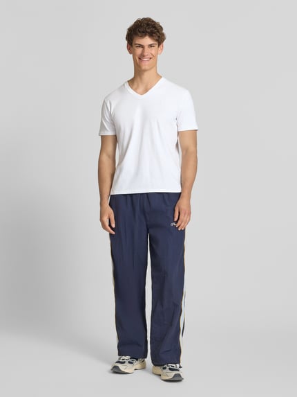 Männermodel trägt T-Shirt aus Baumwoll-Leinen-Mix mit V-Ausschnitt von Superdry, weiß, Regular-Fit, sichtbares Stitching, Rückenlänge 68 cm bei Größe M, Ganzkörperansicht von vorne.