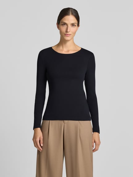 Frauenmodel trägt Slim Fit Longsleeve aus reiner Baumwolle von Christian Berg Woman, taillierte Passform, Rundhalsausschnitt, schwarze Farbe, glatte Struktur, Ganzkörperansicht von vorne.