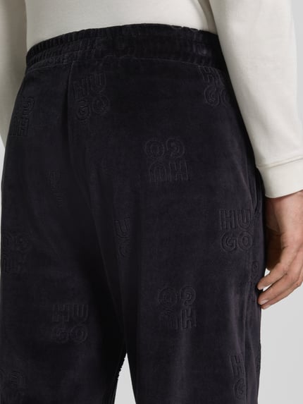 Männermodel trägt Regular Fit Sweathose mit Samtstruktur von HUGO, unifarbene Struktur, elastischer Bund, Nahaufnahme Rückansicht.
