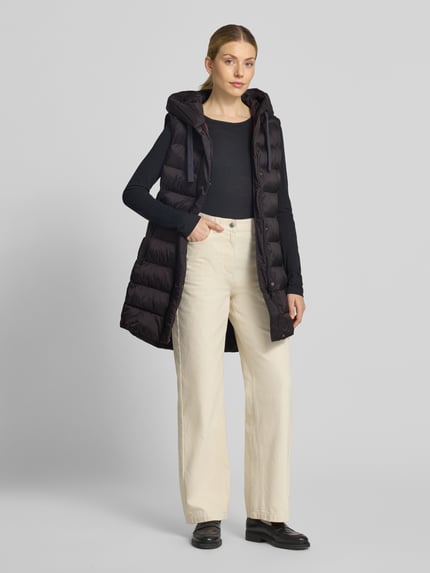 Vrouwenmodel draagt Regular Fit bodywarmer in stiksels van FUCHS SCHMITT, zwart, met capuchon en steekzakken met ritssluiting, ruglengte 77 cm, schouderbreedte 41 cm, borstwijdte 51 cm, ganzekijk van voren.