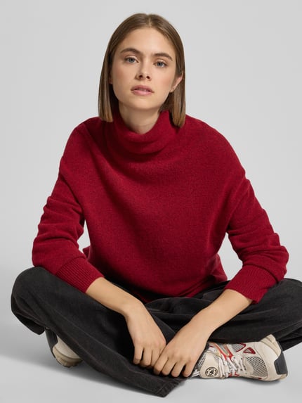 Frauenmodel trägt Regular Fit Rollkragenpullover aus Schurwoll-Mix von Marc O'Polo Denim in rot meliert, Stricktextur, Nahaufnahme Oberkörper.