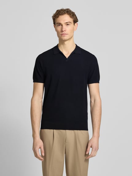 Męski model nosi Regular Fit Poloshirt aus Lyocell-Mix mit Seiden-Anteil von Profuomo, czarny, fakturowany wzór, dekolt w serek, długość tyłu 67 cm w rozmiarze M, widok całej sylwetki z przodu.