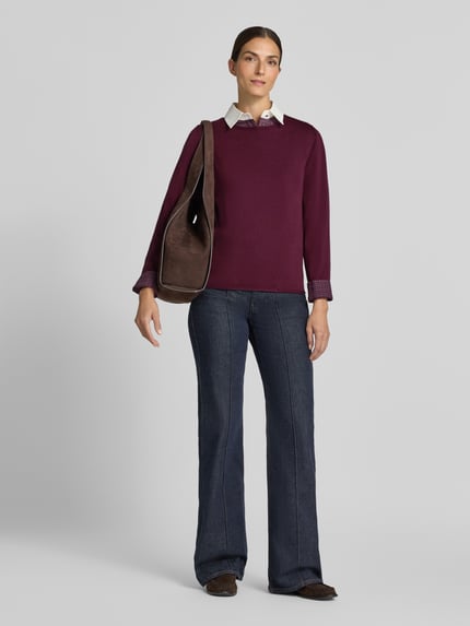 Kobiece modelka nosi Regular Fit Pullover aus Baumwoll-Viskose-Mix od s.Oliver RED LABEL, bordowy sweter, dżinsy, widok całej sylwetki z przodu.