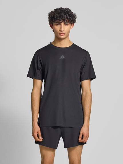 Männermodel trägt Regular Fit Sport T-Shirt mit Label Print von adidas Training, Optik: Unifarben, Ganzkörperansicht von vorne.