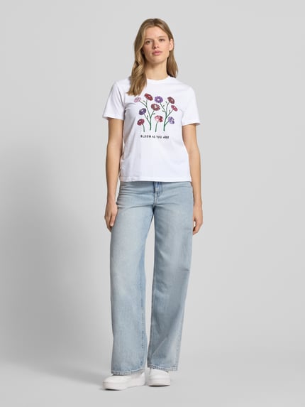 Frauenmodel trägt Damen T-Shirt von Only, Modell 'KITA', Optik: Unifarben, Motiv-Print mit Pailletten, Slim-Fit, Rundhals, Kurzarm, Jersey aus reiner Baumwolle, Ganzkörperansicht von vorne.