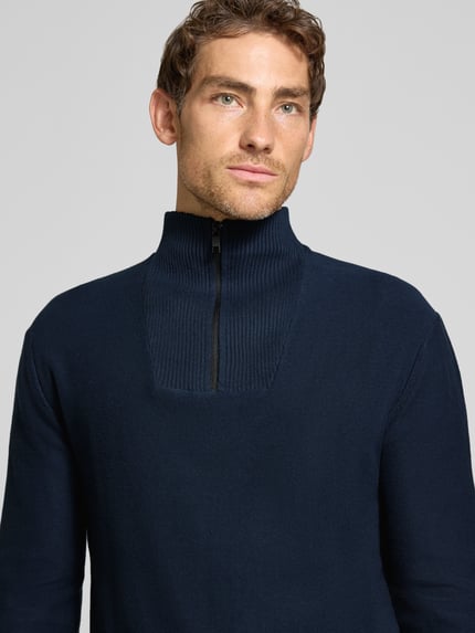 Männermodel trägt Troyer aus reiner Baumwolle mit Reißverschluss-Detail von TOM TAILOR DENIM, dunkelblau, Strickoptik, Nahaufnahme Oberkörper.