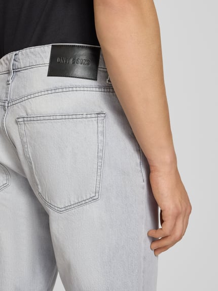 Männermodel trägt Straight Fit Jeans aus reiner Baumwolle Modell 'EDGE' von Only & Sons, helle Denim-Optik, Detailaufnahme Rückansicht.
