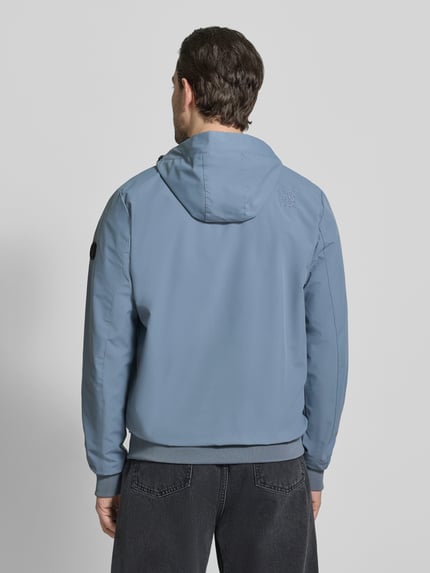 Męski model nosi kurtkę Jacke mit Reißverschlusstaschen Modell 'MATTEO' von CARS JEANS, mieszanka materiałów z dodatkiem streczu, krój regular fit, kaptur z tunelem, odcień błękitu, struktura gładka, długość tyłu 70 cm, szerokość ramion 44 cm, szerokość w rozmiarze M 50 cm, długość rękawów 70 cm, widok całej sylwetki od tyłu.