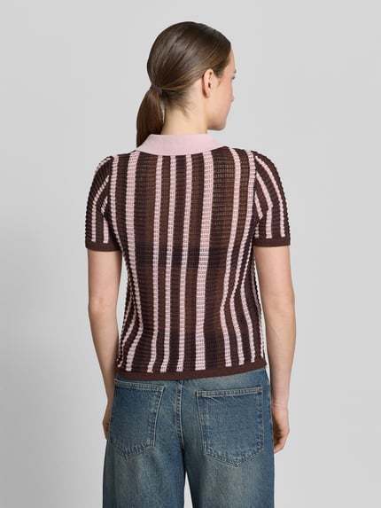 Frauenmodel trägt Modern Fit Poloshirt in Strick-Optik Modell 'PETRA' von Mango, braun-rosafarbene Streifen, Baumwoll-Mix, Ganzkörperansicht Rückansicht. Rückenlänge bei Größe S: 53 cm, Ärmellänge bei Größe S: 23 cm, Polokragen, kurze Knopfleiste.