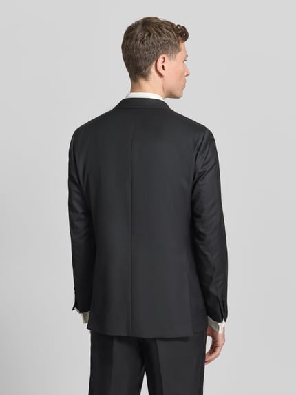 Männermodel trägt 1-Knopf-Sakko mit Reverskragen von Wilvorst aus schwarzem Baumwoll-Mix, Regular Fit, Ganzkörperansicht Rückansicht.