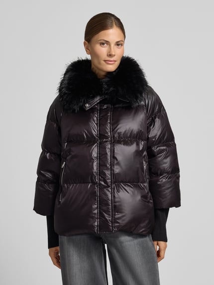 Kobiece model nosi kurtkę pikowaną z wypełnieniem puchem i pierzem, kołnierz ze sztucznego futra, ROCKANDBLUE Steppjacke mit Kunstfell Modell 'Mila', czarny połysk, kieszenie zapinane na zamek błyskawiczny, krój regular fit, widok całego przodu, Ganzkörperansicht von vorne. Długość tyłu w rozmiarze 36: 61 cm, szerokość ramion w rozmiarze 36: 43 cm, szerokość w rozmiarze 36: 58 cm, długość rękawów w rozmiarze 36: 46 cm.