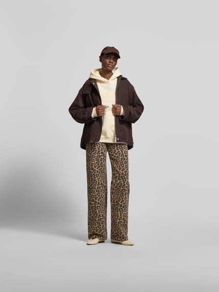 Frauenmodel trägt Oversized Hoodie aus reiner Baumwolle von Anine Bing in Creme mit Känguru-Tasche, Label-Detail, elastische Abschlüsse, Rückenlänge 63 cm bei Größe S, Ganzkörperansicht von vorne.