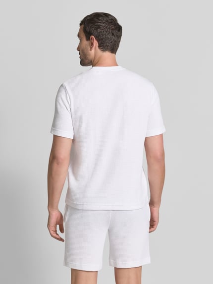 Männermodel trägt weißes Herren T-Shirt aus Baumwoll-Mix Modell 'AUSTIN' von HUGO, feine Waffelstruktur, Ganzkörperansicht Rückansicht.