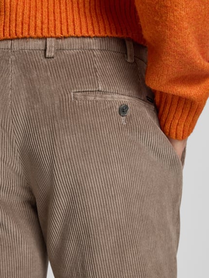 Männermodel trägt Cordhose mit Gesäßtaschen Modell 'PARMA' von Hiltl aus reiner Baumwolle, braun, Struktur durch Rippen, Detailaufnahme.