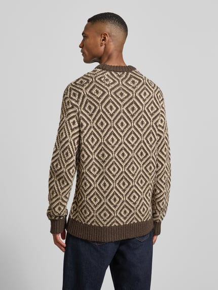 Männermodel trägt Relaxed Fit Strickpullover aus Woll-Mix Modell 'REMI' von SELECTED HOMME mit Allover-Muster in Braun und Creme, ganzkörper Rückansicht.