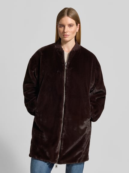 Frauenmodel trägt Regular Fit Mantel aus Kunstfell Modell 'Wender' von Beaumont Amsterdam in Dunkelbraun, glatte Struktur, Ganzkörperansicht von vorne, Stehkragen, Zweiwege-Reißverschluss, Rückenlänge 92 cm, Schulterbreite 54 cm, Brustweite 46 cm, Ärmellänge 62 cm.