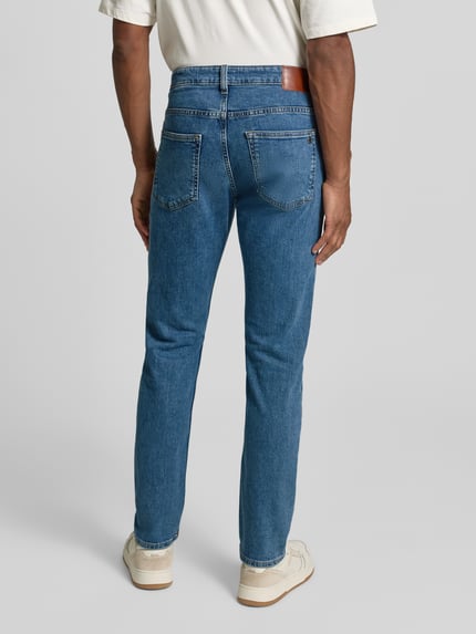 Männermodel draagt Slim Fit Jeans aus Baumwoll-Mix Modell 'DELAWARE' van BOSS Orange, denim melange, 5-pocket, label patch, Ganzkörperansicht Rückansicht.