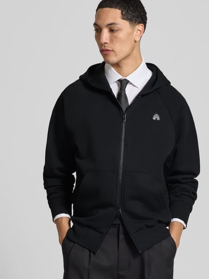 Männermodel trägt Sweatjacke mit Kapuze von Moose Knuckles in Schwarz, Baumwoll-Mix, lockerer Schnitt, Ganzkörperansicht von vorne.