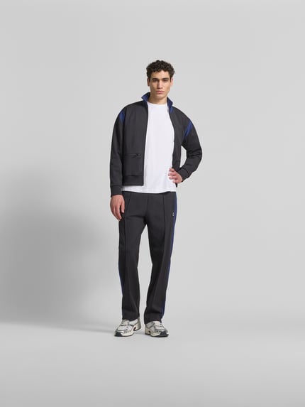 Männermodel trägt Regular Fit sweatjack met opstaande kraag van Kenzo, donkerblauw met blauwe accenten, steekzakken met ritssluiting, ritssluiting, elastische boorden, ruglengte maat M 67 cm, schouderbreedte 51 cm, mouwlengte 61 cm, Ganzkörperansicht von vorne.