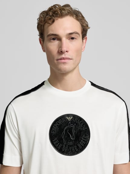 Männermodel trägt weißes Herren T-Shirt mit schwarzem Label-Detail von Emporio Armani, Lyocell-Baumwoll-Mix, Regular Fit, Nahaufnahme Oberkörper.