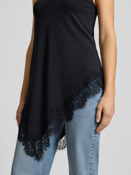 Vrouwenmodel draagt Trägertop met Spitzenbesatz van Gina Tricot, zwart met kanten rand, losse fit, spaghetti-bandjes, detailopname bovenlichaam.