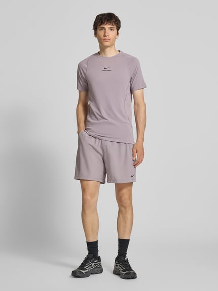 Männermodel trägt Shorts mit Logo-Print und Eingrifftaschen von NIKE TRAINING in Flieder, Gerader-Schnitt, Ganzkörperansicht von vorne. Bundweite 41 cm, Innenbeinlänge 19 cm, elastischer Bund mit Kordelzug.
