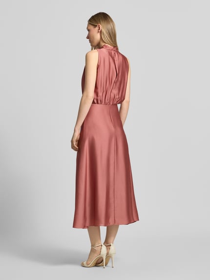Frauenmodel trägt Cocktailkleid mit Stehkragen von Swing, taillierte Passform, Midikleid, Rückenreißverschluss, Unterkleid, Rückseite, Ganzkörperansicht Rückansicht.