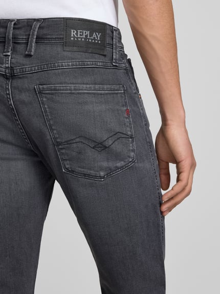 Mężczyznamodel nosi Slim Fit Jeans im 5-Pocket-Design Modell 'Anbass' von Replay, dopasowany krój, 5 kieszeni, zapięcie na guzik i zamek błyskawiczny, szerokość w rozmiarze 32/32: 43 cm, długość wewnętrzna nogawki w rozmiarze 32/32: 83 cm, detailaufnahme tyłu bioder.