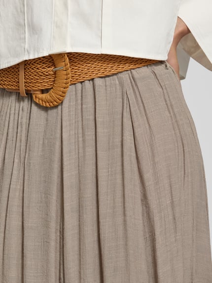 Frauenmodel trägt Midirock aus Viskose-Mix mit Gürtel von Apricot in Beige, A-Linie, feine Textur, Damen Gürtel sichtbar, Nahaufnahme Oberkörper.
