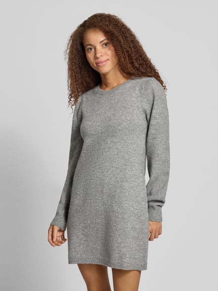 Frauenmodel trägt Strickkleid mit Puffärmeln von PIECES in grau melierter Strickoptik, Rundhalsausschnitt, gerippte Abschlüsse, Ganzkörperansicht von vorne.