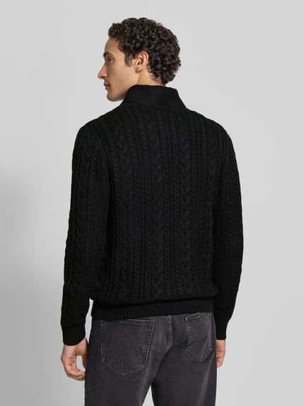 Mężczyzna nosi sweter z dzianiny z mieszanki materiałów z bawełną, krój slim fit, ścieg warkoczowy, szalowy kołnierz, zapięcie na guzik, model 'CALLUM' od JACK & JONES premium, widok całej sylwetki od tyłu.