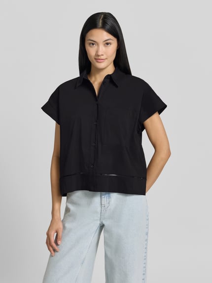 Frauenmodel trägt Relaxed Fit Hemdbluse mit Loch-Stitching Modell 'Fallerie' von OPUS in Schwarz, kurzärmelig auf hellem Hintergrund, Nahaufnahme Oberkörper. Elastischer Baumwoll-Mix, Knopfleiste, Hemdblusenkragen, Rückenlänge bei Größe 36: 55 cm.