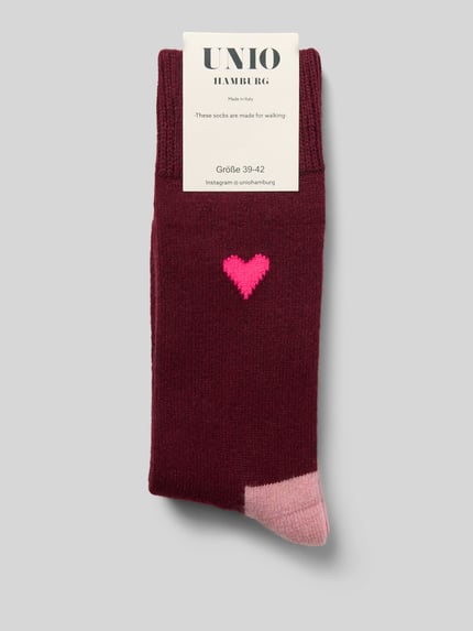 Produktfoto, Socken mit Kaschmir-Anteil und Motiv-Stitching von UNIO HAMBURG in Dunkelrot mit rosa Herz und farblich abgesetzter Spitze, Damen Socken aus Woll-Mix mit gerippten Bündchen auf hellgrauem Hintergrund.