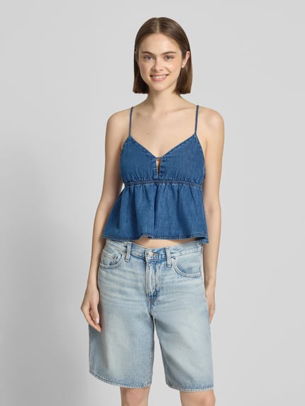 Frauenmodel trägt Denim Blusentop aus reiner Baumwolle von Tommy Jeans in Blau mit V-Ausschnitt und Spaghettiträgern, Ganzkörperansicht von vorne.