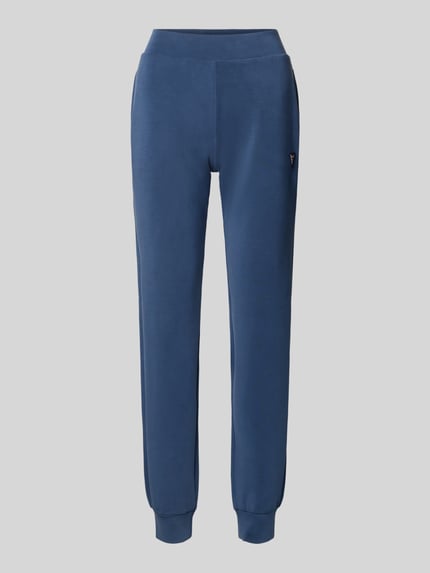 Produktfoto, blaue Sweatpants mit Label-Detail von Guess Activewear, gerader Schnitt, elastischer Bund, seitliche Taschen, glatte Textur