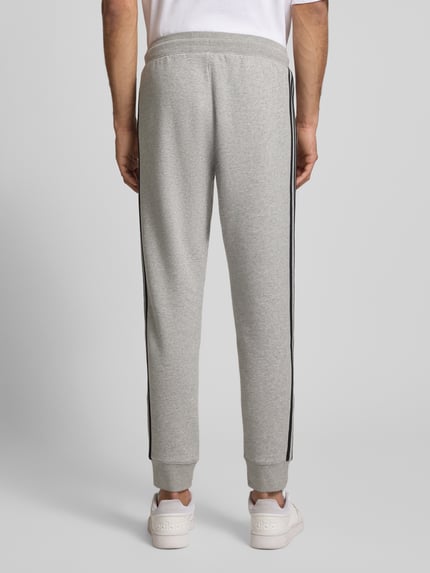 Männermodel trägt Sweatpants mit elastischem Bund von adidas Originals in Hellgrau, Baumwoll-Mix, Lockerer-Schnitt, Label-Stitching, Eingrifftaschen, Innenbeinlänge bei Größe M 74 cm, Ganzkörperansicht Rückansicht.