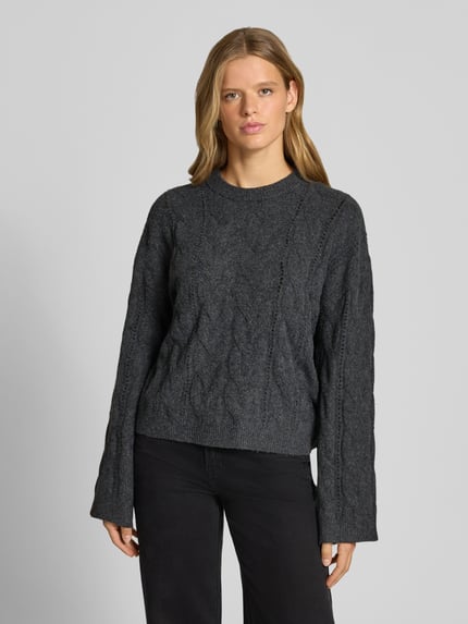 Modelka nosi ciemnoszary sweter z okrągłym dekoltem i widocznym splotem, Relaxed Fit Pullover mit Rundhalsausschnitt Modell 'KATHY' od PIECES, damski sweter, Ganzkörperansicht von vorne.