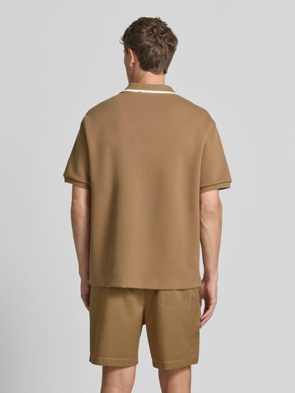 Männermodel trägt Loose Fit Poloshirt von Lacoste in Beige mit glatter Textur, Herren Poloshirt, Ganzkörperansicht Rückansicht.