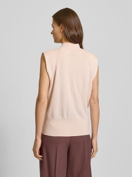 Vrouwenmodel draagt Regular Fit Spencer uit puur kasjmier Model 'FUTRANI' van BOSS, look: effen, fijngebreid, col, geribde rompzoom, applicatie met labelstitching, kleur lichtbeige, materiaal: zuiver kasjmier, Ganzkörperaanzicht achteraan.