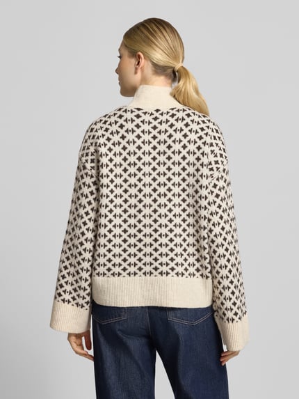 Frauenmodel trägt Pullover mit Jacquardstruktur Modell 'VMBIRCH' von VERO MODA, geometrisches Allover-Muster, Strickoptik, Ganzkörperansicht Rückansicht.