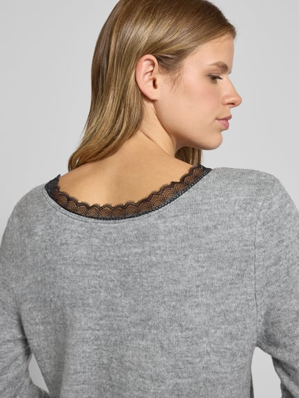Frauenmodel trägt tailliertes Strickkleid mit V-Ausschnitt Modell 'TAMMY' von Only in grauer Melange mit Spitzenbesatz, Rückansicht.