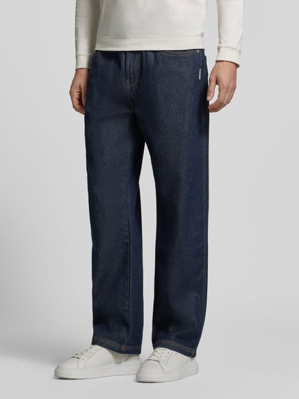 Männermodel trägt Regular Fit Jeans mit Label-Patch von RETERNITY in Raw Denim-Optik, Kontrastnähte, 5-Pocket-Design, Ganzkörperansicht von vorne.