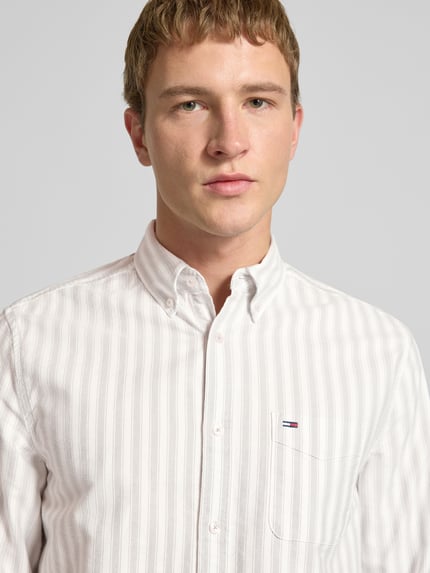 Männermodel trägt Regular Fit Freizeithemd aus reiner Baumwolle von Tommy Jeans, Optik:Allover-Muster, gestreift, Nahaufnahme Oberkörper.