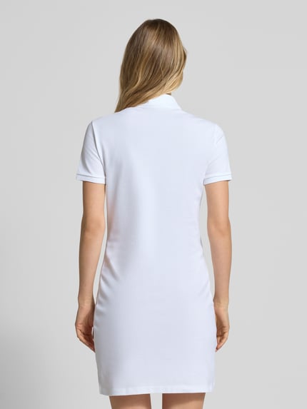 Frauenmodel trägt Slim Fit Polokleid aus Baumwoll-Mix von Lacoste in Weiß, unifarben, kurze Ärmel, Piqué-Struktur, Ganzkörperansicht Rückansicht.