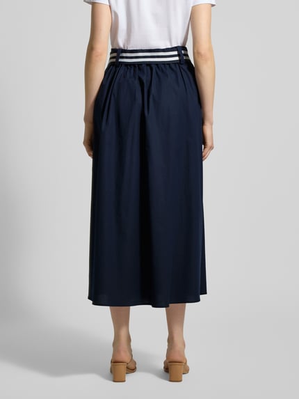 Vrouwenmodel draagt Midirok met elastische band en strikceintuur van More & More, mix van katoen en elastaan, A-lijn, totale lengte maat 36: 86 cm, bandwijdte maat 36: 37 cm. Volledige lichaamsaanzicht achterzijde.